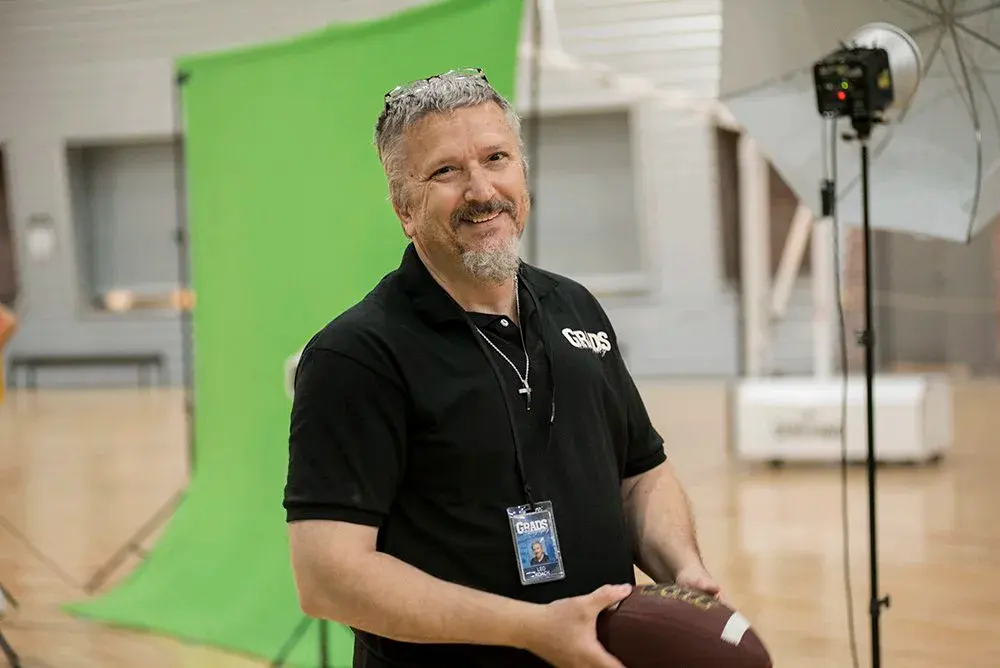Grads photographer with a football at a green-screen set