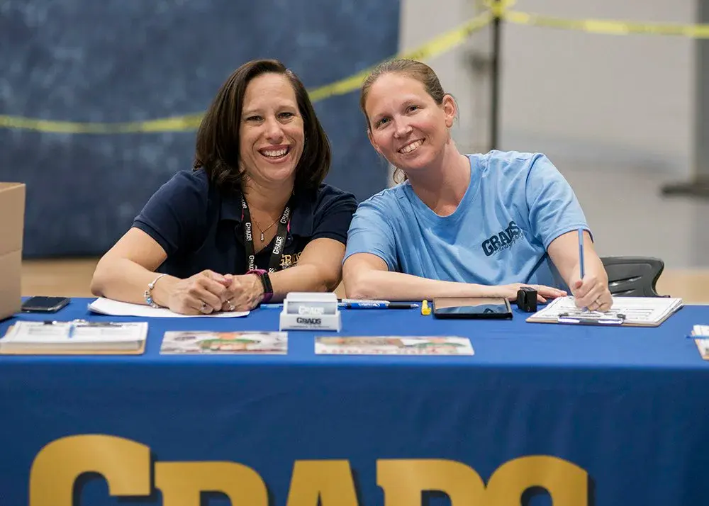 Two Grads team members at a school event table