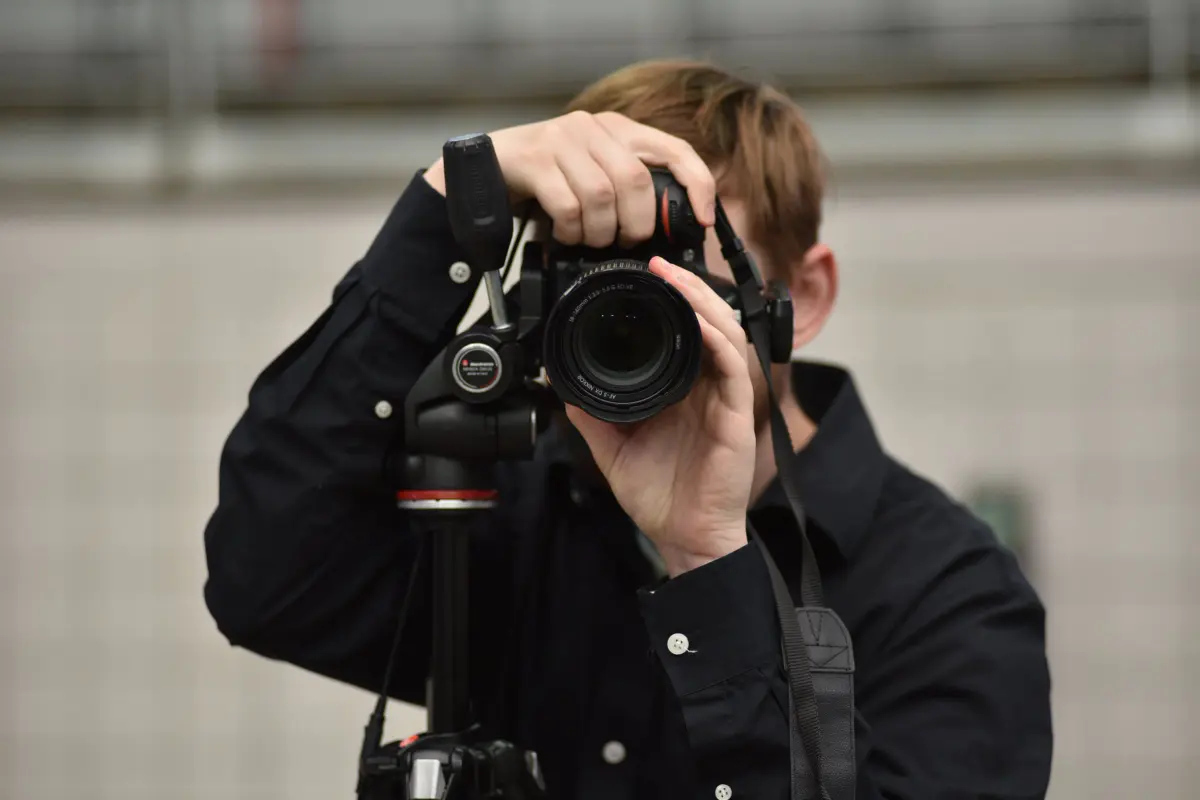 A Grads photographer looking through a camera on a tripod