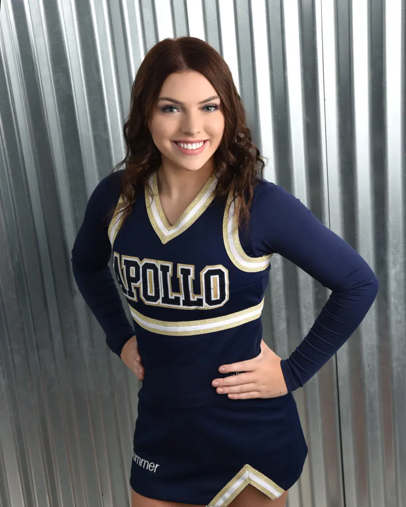 Cheerleader smiling with hands on hips, metal panel backdrop