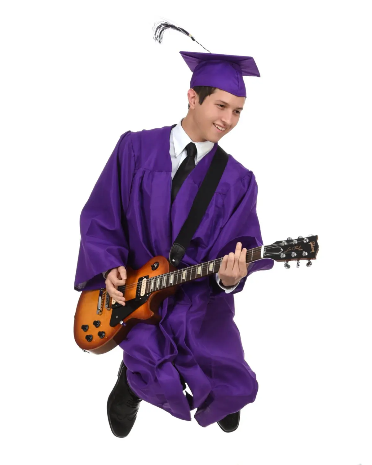 Graduate in purple cap and gown with tie, mid-jump playing an electric guitar, cut out on pure white seamless