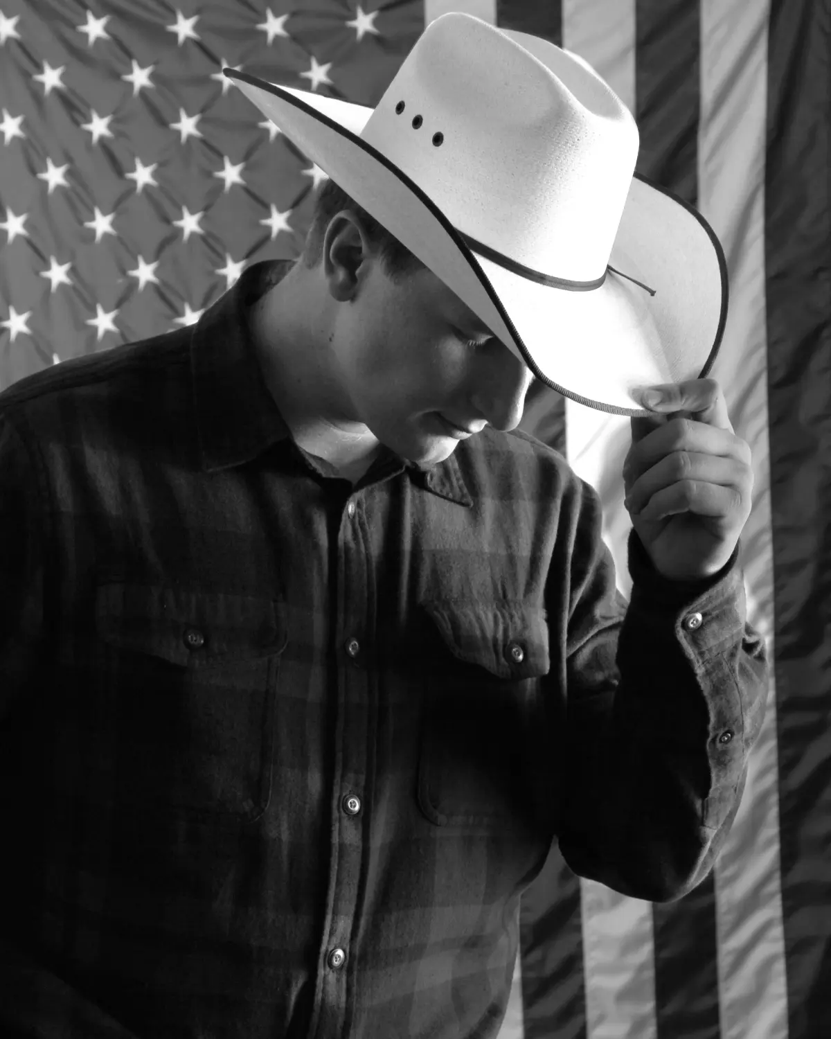 Senior in a cowboy hat, black and white, flag backdrop