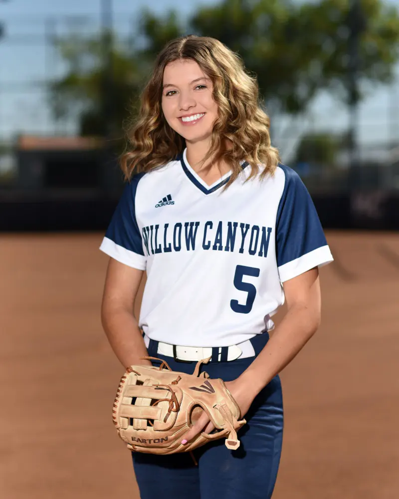 Softball player holding her glove on the infield