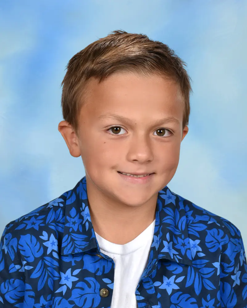 School portrait of a boy in a blue print shirt on a sky blue backdrop