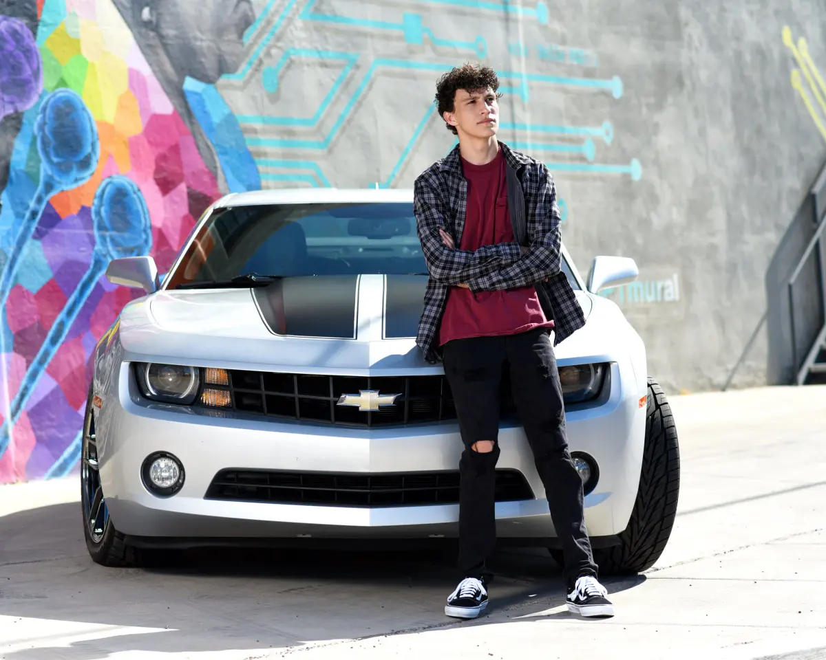 Young man in a plaid flannel over a maroon tee and ripped black jeans