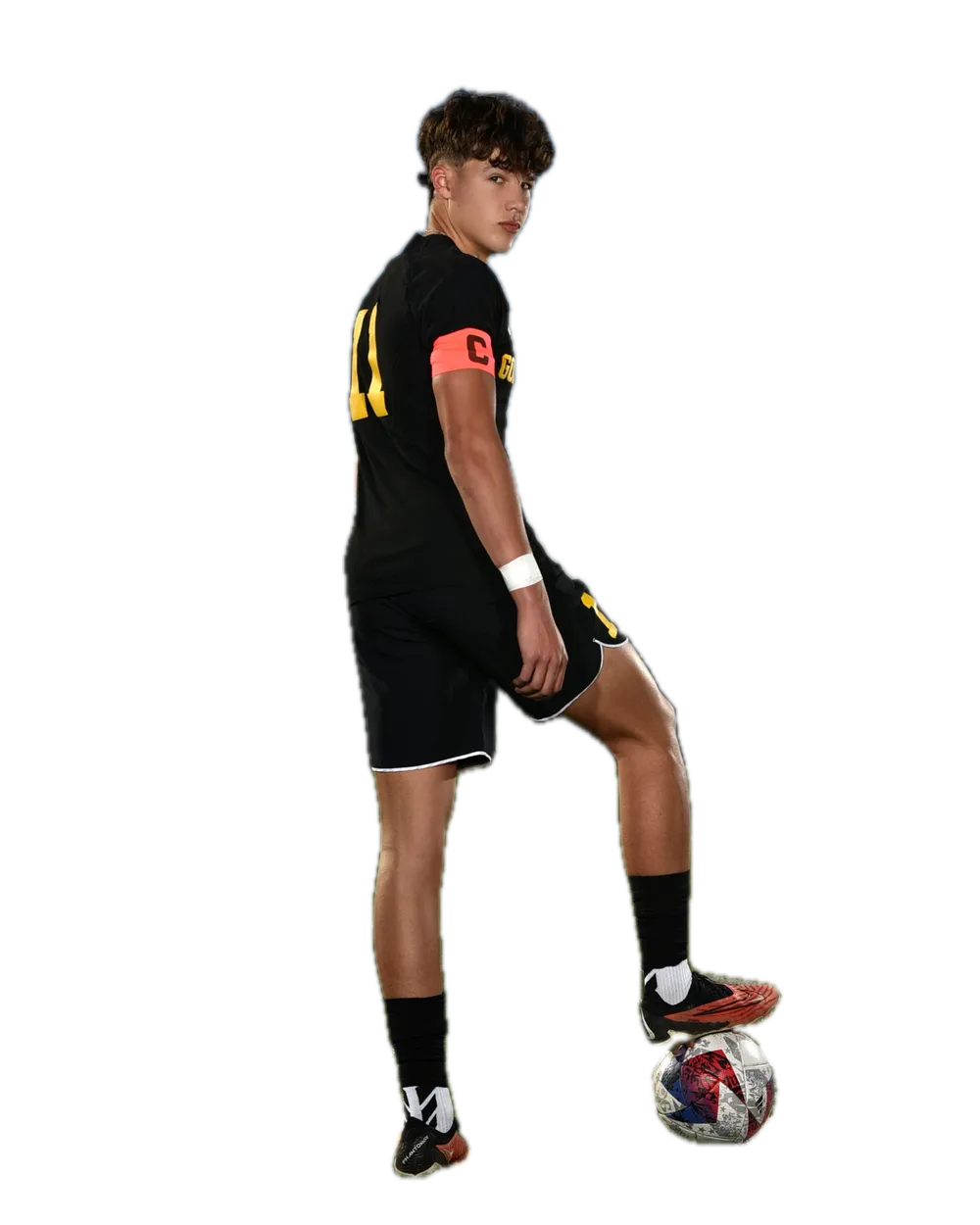 Soccer player looking back over his shoulder, one foot on the ball