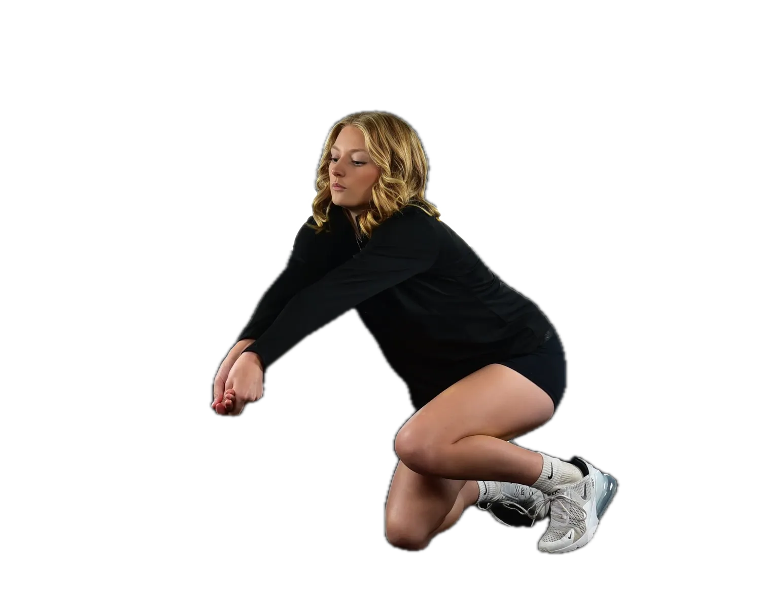 Volleyball player in black, low on one knee in a dig, arms extended, volleyball frozen mid-air beside her