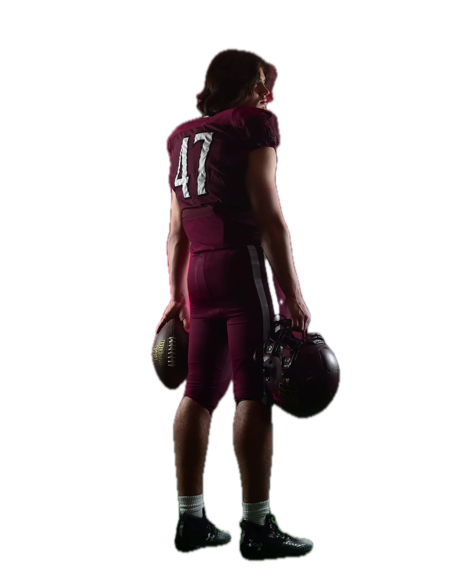 Football player seen from behind, holding a ball and his helmet