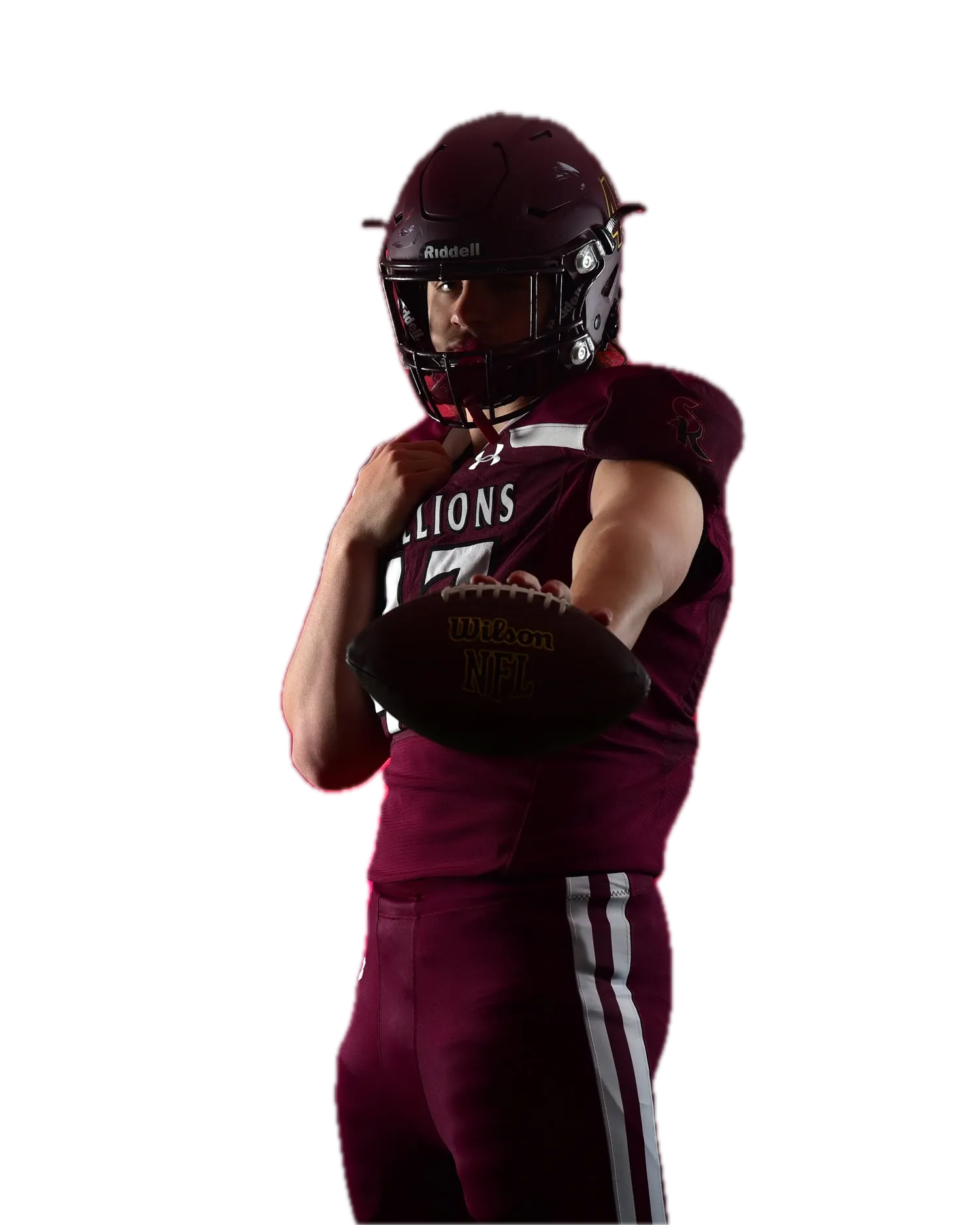 Football player in a maroon helmet and jersey (partial team name visible) extending a football toward the camera, with pink/red haze lighting behind