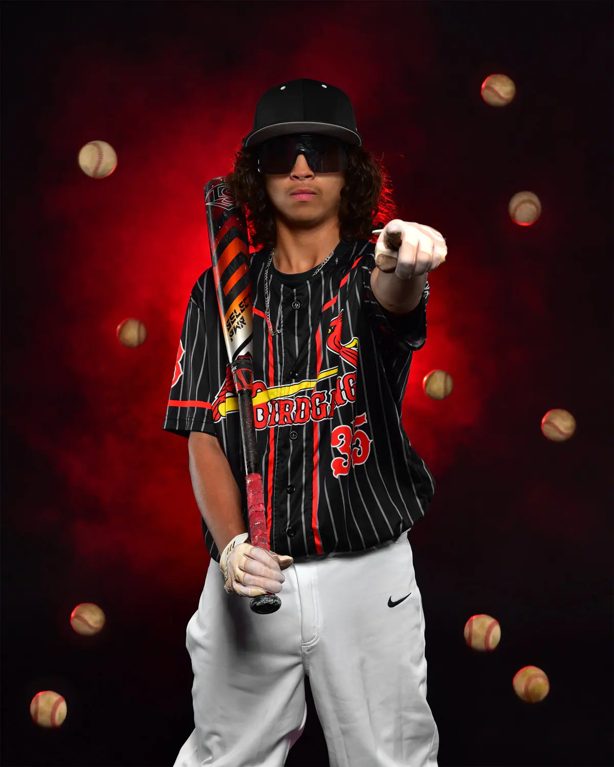 Baseball player in black pinstripe 'Birdgang 35' jersey, white pants, sunglasses and cap, bat on shoulder, pointing at camera