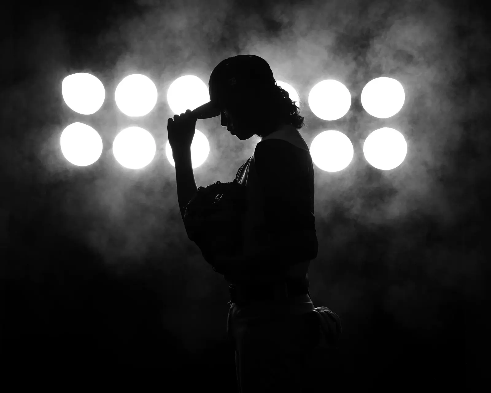 Baseball player silhouetted against stadium lights and smoke