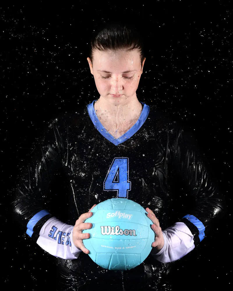 Volleyball player holding the ball under falling water