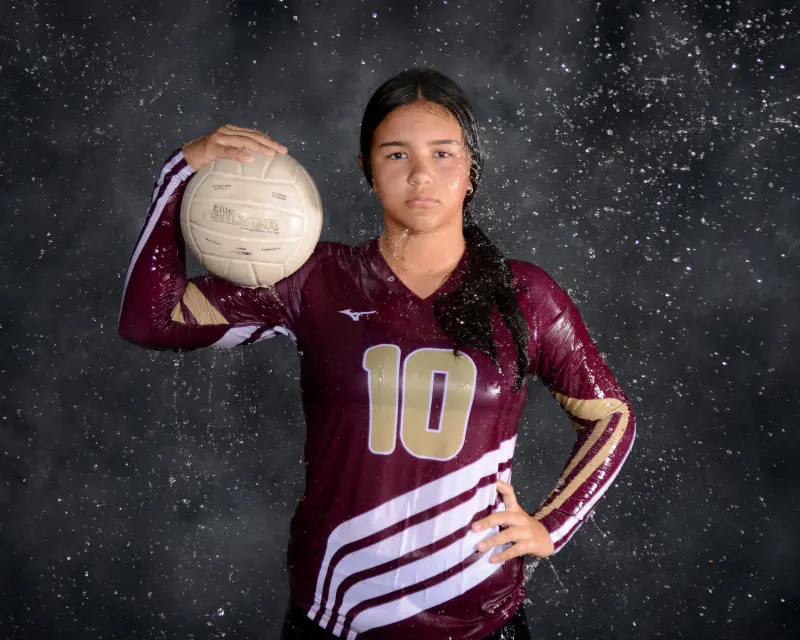 Volleyball player with the ball on her shoulder, dark backdrop