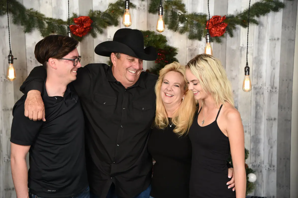 Family of four adults in black outfits (young man with glasses, man in black cowboy hat